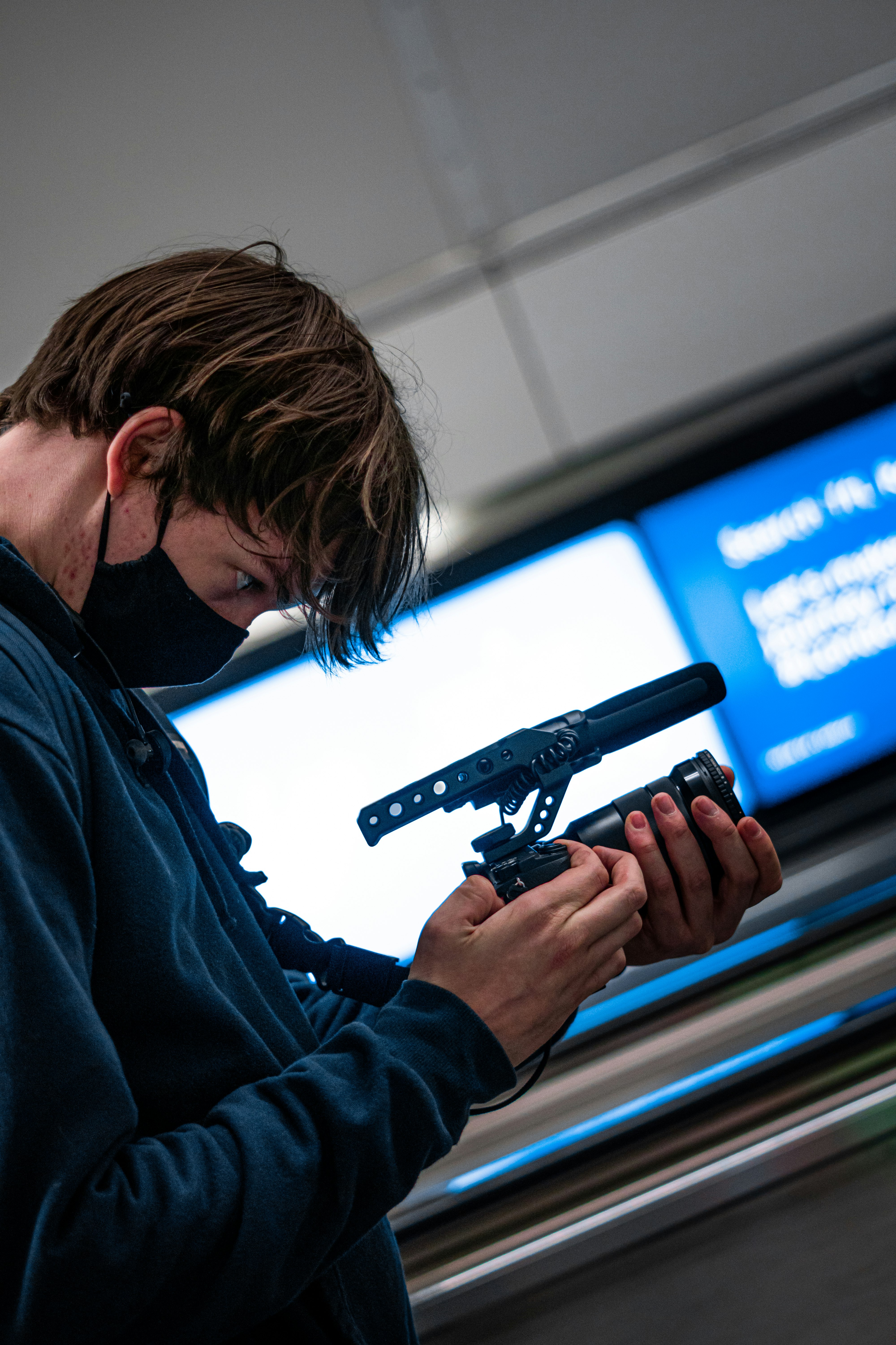 man in blue jacket holding black video camera